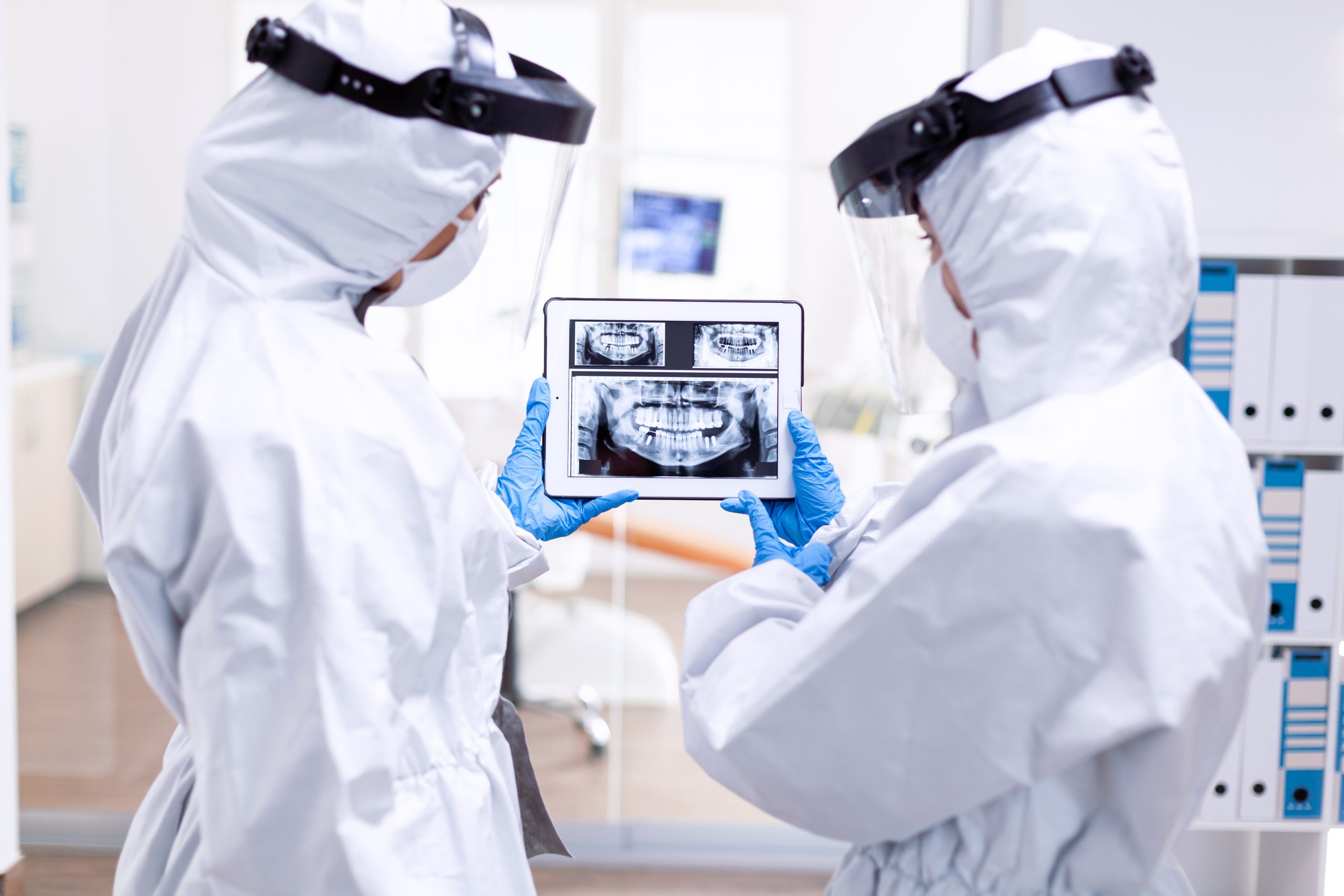 Stressed doctors dressed in protection suit looking at digital dental x-ray
